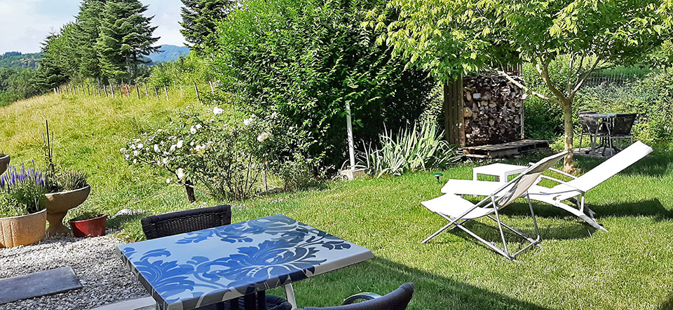 Espace extérieur détente avec mobilier de jardin chaise longue relax table de jardin pour petit déjeuner entouré de verdure et d'abres fruitiers